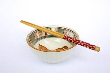Two bowls with horses and traditional tribal motifs come with chopsticks on each bowl. This crockery set is a gift. Isolated on white background.