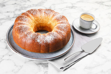 Freshly baked sponge cake, server and coffee on white marble table