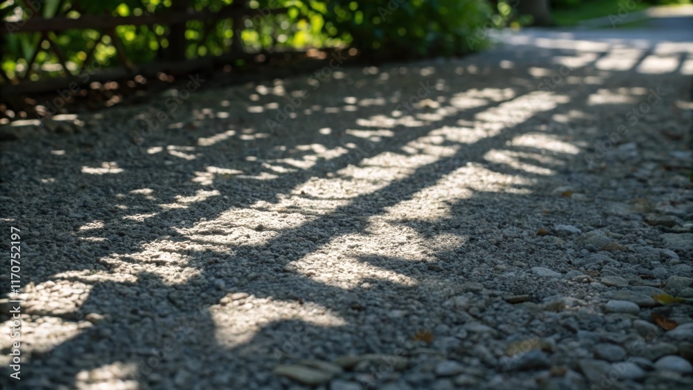 Poster an artistic closeup focusing on the shadows cast by the gravel as sunlight filters through nearby fo