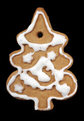 Christmas gingerbread in the shape of a decorated fir tree in white icing isolated on black. homemade christmas sweets close-up