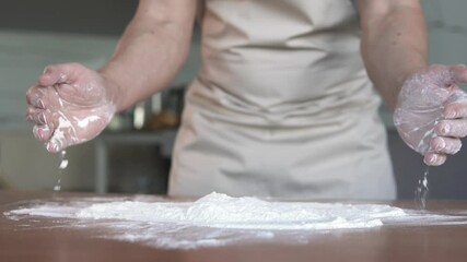 Experienced professional baker holding a handful of flour. Preparation for baking bread and pizza. Slow motion.