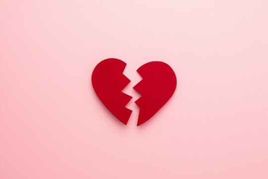 Broken Red Paper Heart Symbol on a Soft Pink Background