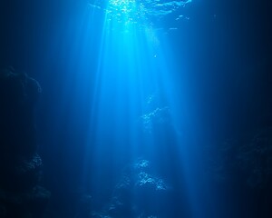 Sunbeams penetrate deep ocean, illuminating dark underwater cavern.