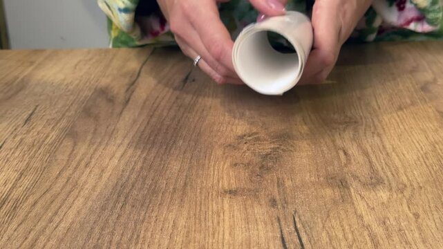 A woman takes a sheet of window stickers out of the packaging. The stickers are in the shape of snowflakes. Close-up. Vertical video.