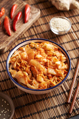 Fermented kim chi in a bowl on a table with chilli peppers, sesame seeds and ginger