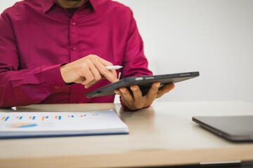 Fototapeta premium A focused man works diligently in his office, reviewing numerous accounting documents on his desk. His goal is to ensure accuracy and precision, avoiding errors in critical financial data.