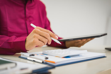 A focused man works diligently in his office, reviewing numerous accounting documents on his desk....