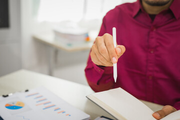 A focused man works diligently in his office, reviewing numerous accounting documents on his desk. His goal is to ensure accuracy and precision, avoiding errors in critical financial data.