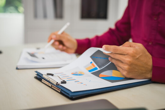A focused man works diligently in his office, reviewing numerous accounting documents on his desk. His goal is to ensure accuracy and precision, avoiding errors in critical financial data.