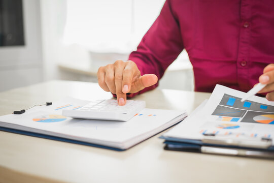 A focused man works diligently in his office, reviewing numerous accounting documents on his desk. His goal is to ensure accuracy and precision, avoiding errors in critical financial data.