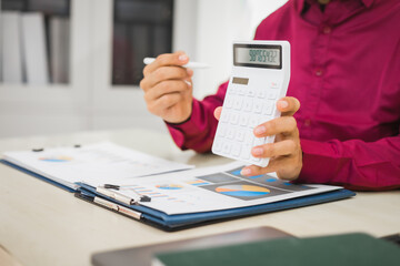 A focused man works diligently in his office, reviewing numerous accounting documents on his desk....
