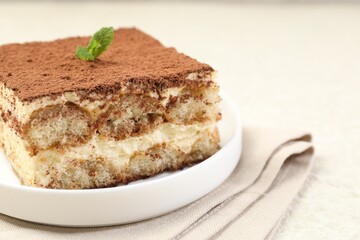 Delicious tiramisu with mint on light table, closeup
