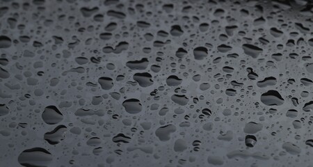 Water drops on grey glass surface, closeup