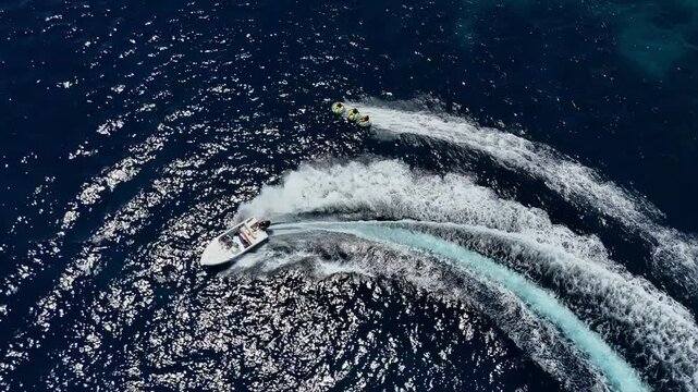 Friends are having fun on an inflatable ringo in the middle of the sea.
