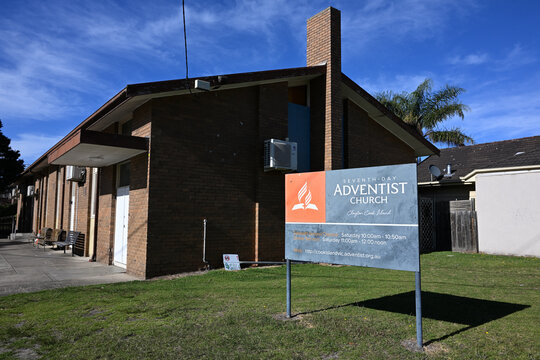 Exterior of Cook Island Seventh-day Adventist Church, with contemporary grey and orange Protestant Christian-style signage in front of the building