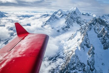 A red plane is flying over a mountain range