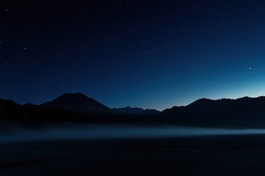 A mountain range is silhouetted against a dark sky - Powered by Adobe