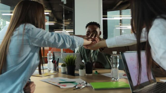 Office workers doing team building exercise stacking hands together in the unifying spirit of creativity and common cause.