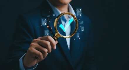Businessman using a magnifying glass to check digital data accuracy