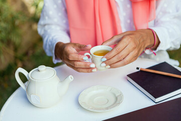 Portrait of a young and beautiful Muslim woman smiling while drinking tea in a garden