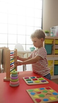 Boy playing in indoor kindergarten with educational toys, showing child development with wooden puzzles, abacus, and colorful stacking rings on a bright, sunny day