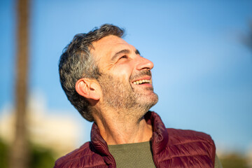Smiling man looking up outdoors on sunny day
