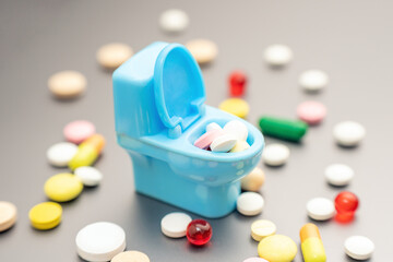 Pills in a small toy toilet. Expired harmful medical drugs