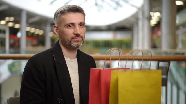 A man examines the contents of his shopping bags, holding a ten-dollar bill in his hand. The scene captures the moment of reflecting on spending during a shopping trip in a brightly lit retail