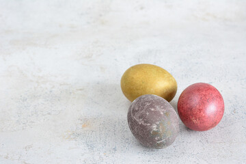 a golden, red and gray eggs are on the marble background copy space 