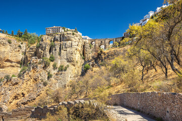 The Puente Nuevo bridge in El Tajo gorge in Ronda town in Spain. Ancient bridge spanning a dramatic gorge, with a village perched on the cliffs. A sunny day in a historical location.