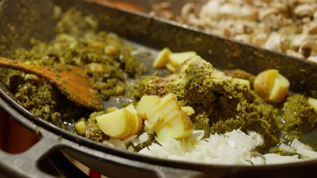 Slow Motion of cooking and making kale next to cham in a very big pan with onions and potatos. Making kale with potatoes and onions in a very big pan