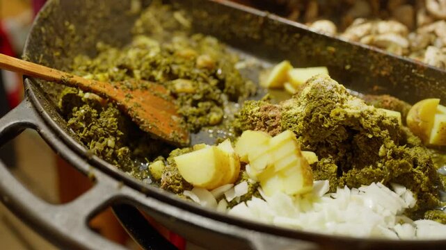 Slow Motion of cooking and making kale next to cham in a very big pan with onions and potatos. Making kale with potatoes and onions in a very big pan