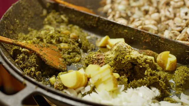 Slow Motion of cooking and making kale next to cham in a very big pan with onions and potatos. Making kale with potatoes and onions in a very big pan