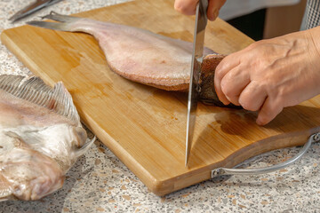 Chef cuts fresh fish into pieces with a knife