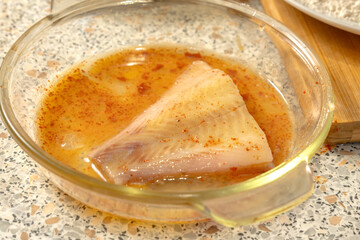 Piece of fish lies in Liaison sauce - a mixture of raw eggs, salt, paprika before frying. Close-up