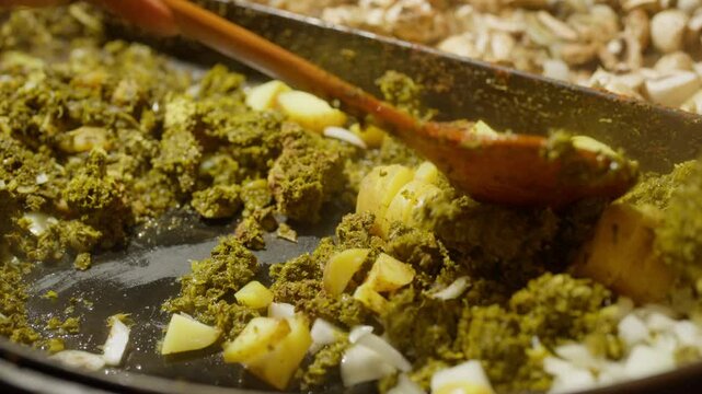 Slow Motion of cooking and making kale next to cham in a very big pan with onions and potatos. Making kale with potatoes and onions in a very big pan