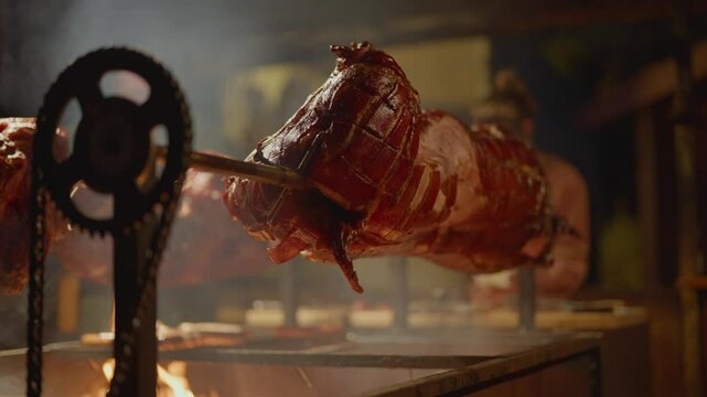 Roasted a whole big pig on fire. Grilled on a big skewer. Roasting piglet on a spit turns slowly roasting it. Barbecue. Street food. 4k. Lechon or Suckling popular dish. pigs roasting on fire pit and 