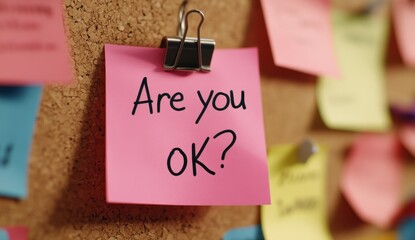 Pink sticky note asking Are you OK on corkboard with colorful notes