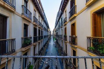 Narrow street with traditional buildings and wrought iron balconies in San Sebastian, Spain. Urban architecture and cityscape