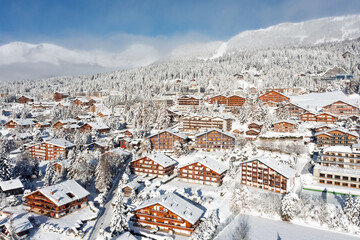 Skiing resort of Crans Montana covered by snow in winter. Chalets, fir forest and slopes