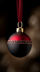 A red and black christmas ornament hanging from a red ribbon
