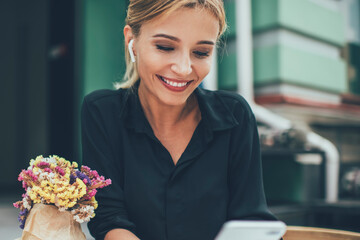 Happy female millennial watching positive influence streams via smartphone application enjoying...
