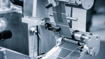 Fragment of the conveyor of sticking labeling machine. Abstract industrial background.