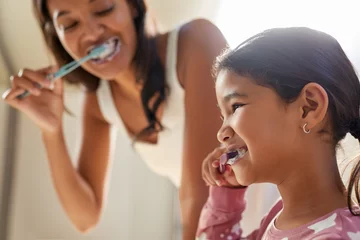Indian mother and cute little girl brushing teeth together