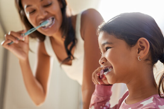 Indian mother and cute little girl brushing teeth together