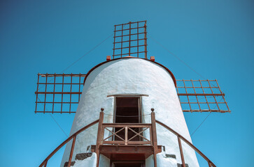 Rustic White Windmill with Wooden Accents Standing Against a Pristine Blue Sky – A Timeless Piece...