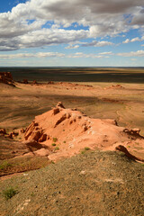 The striking red sandstone formations of the Flaming Cliffs in the Gobi Desert, Mongolia, under a vast blue sky.
