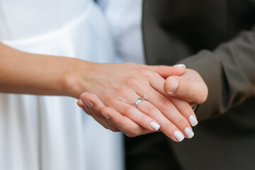 Obraz premium Man holds girl's hands with engagement ring and admires them. Outdoor wedding ceremony close-up portrait