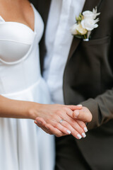 Man holds girl's hands with engagement ring and admires them. Outdoor wedding ceremony close-up portrait