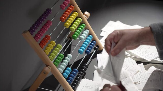 A man counts expenses on a wooden abacus. A man keeps records. A wooden abacus instead of a calculator. A man is angry and upset because of his unsuccessful attempt.